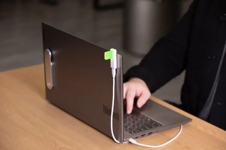 Luxafor busy light for desk plugged into a laptop via USB, glowing green to signal availability at an individual workstation